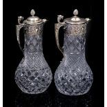 TWO CUT GLASS SILVER PLATED LIDDED CLARET JUGS with decorative pineapple finials and lion head