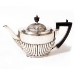 AN OVAL SILVER TEAPOT with gadrooned body, ebonised handle and knop, with marks for London 1917