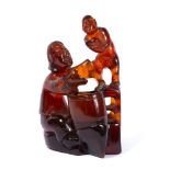 Carved amber figure group Chinese, 19th Century depicting a boy standing on a stool next to a seated