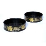 Pair of black lacquered bottle coasters with gilt painted decoration of grape vines, measures 14cm