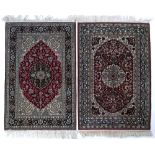 Matched pair of silk Persian rugs each with red ground foliate medallions 93cm x 61cm approx.