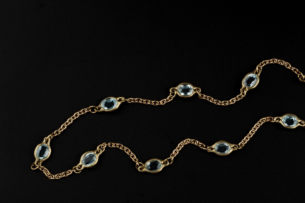 A BLUE TOPAZ SET LONG CHAIN, the 9ct gold trace-link chain spaced by spectacle set oval mixed-cut