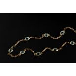 A BLUE TOPAZ SET LONG CHAIN, the 9ct gold trace-link chain spaced by spectacle set oval mixed-cut