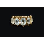 A 19TH CENTURY TOPAZ FIVE STONE RING, the graduated oval mixed-cut topaz of pale blue hues, in