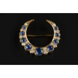 A SAPPHIRE AND DIAMOND CRESCENT BROOCH, alternately set with circular mixed-cut sapphires and