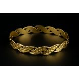 A YELLOW PRECIOUS METAL BANGLE, with pierced and foliate engraved decoration, inner diameter 6.3cm