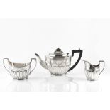 AN EDWARDIAN SILVER THREE PIECE TEA SERVICE, of oval half lobed form, engraved with swags of