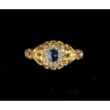 A SAPPHIRE AND DIAMOND CLUSTER RING, the circular mixed-cut sapphire bordered by lasque-cut
