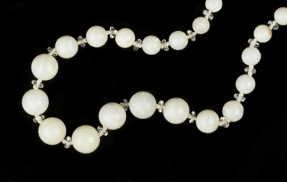 AN OPAL BEAD NECKLACE, the single strand of graduated opal beads with colourless spacers between, on