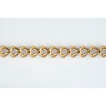 A YELLOW PRECIOUS METAL FANCY-LINK BRACELET, comprising a line of repeating heart-shaped links, with
