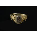 A 19TH CENTURY MEMORIAL RING, centred with a glazed plaited hairwork panel, between pierced and