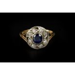 A SAPPHIRE AND DIAMOND PANEL RING, the pierced circular panel centred with a cushion-shaped mixed-