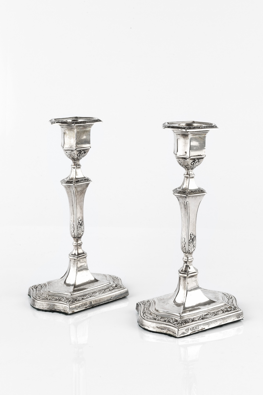 A PAIR OF EDWARDIAN SILVER CANDLESTICKS, with shaped and knopped stems, repoussé decorated with