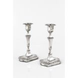 A PAIR OF EDWARDIAN SILVER CANDLESTICKS, with shaped and knopped stems, repoussé decorated with