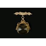 A CITRINE SWIVEL FOB, the faceted citrine to a foliate engraved frame with scrolled surmount,
