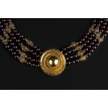 A GARNET MULTI-STRAND BEAD NECKLACE, with fluted spacer beads, to a circular boss-shaped panel