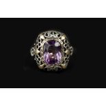 AN ARTS AND CRAFTS AMETHYST PANEL RING, the cushion-shaped panel pierced and engraved with foliage