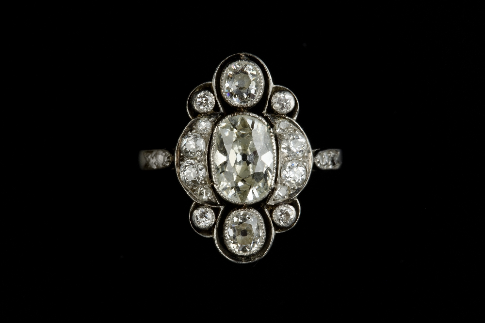 AN EARLY 20TH CENTURY DIAMOND PANEL RING, the openwork panel centred with a trio of cushion-shaped