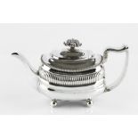 A GEORGE III SILVER TEAPOT, of rounded rectangular outline with gadrooned borders, foliate knop,