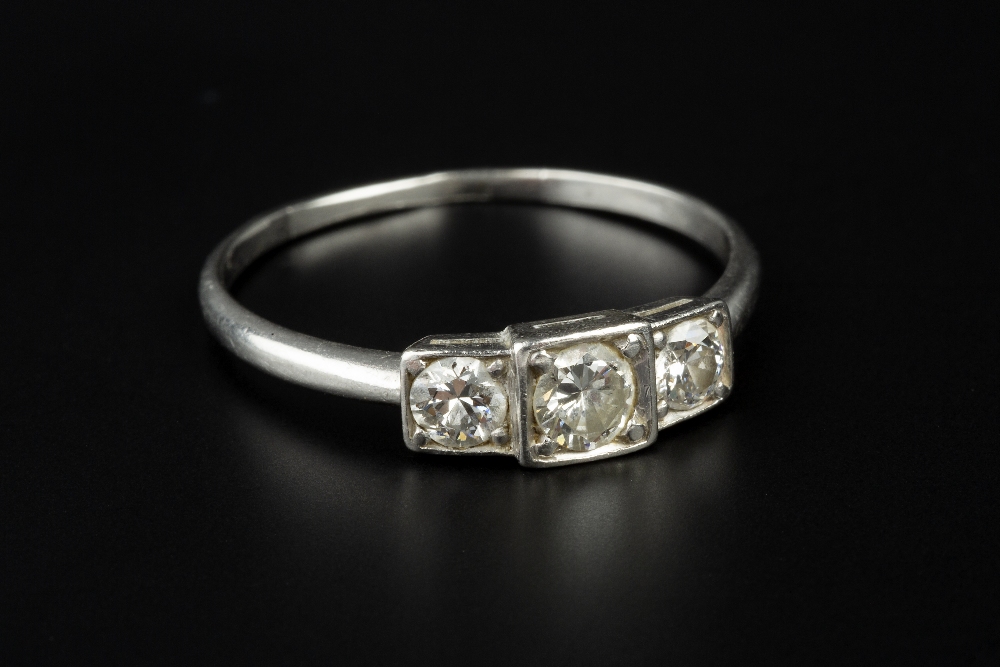 A DIAMOND THREE STONE RING, the graduated round brilliant-cut diamonds in stepped square settings,