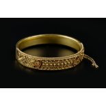 A LATE VICTORIAN BANGLE, of hinged oval form, applied with a frieze of ropetwist wirework, beads and