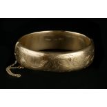 A 9CT GOLD BANGLE, of hinged oval form, with foliate engraved decoration, inner diameter 6.2cm