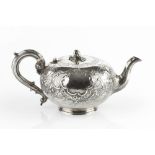 A MID VICTORIAN SILVER TEAPOT, repoussé decorated and chased with flowering foliage and 'C' scrolls,