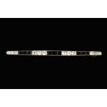 AN ART DECO DIAMOND AND ONYX BAR BROOCH SIGNED BY CARTIER, the tapered and millegrained bar set with