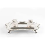 AN EDWARDIAN SILVER INKSTAND, of shaped rectangular outline, with beaded border, on paw feet, fitted