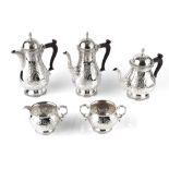 A SILVER FIVE PIECE TEA AND COFFEE SERVICE, of baluster form, engraved and embossed with flowering