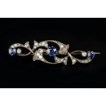 A SAPPHIRE AND DIAMOND PANEL BROOCH, the openwork panel of foliate scrolls, centred with a trio of