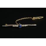 A SAPPHIRE AND DIAMOND BAR BROOCH, the oval mixed-cut sapphire collet set between trios of graduated
