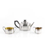 A VICTORIAN SILVER THREE PIECE BACHELOR'S TEA SET, of engraved oval form, the teapot with carved