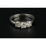 A DIAMOND THREE STONE RING, the graduated round brilliant-cut diamonds in four claw settings,