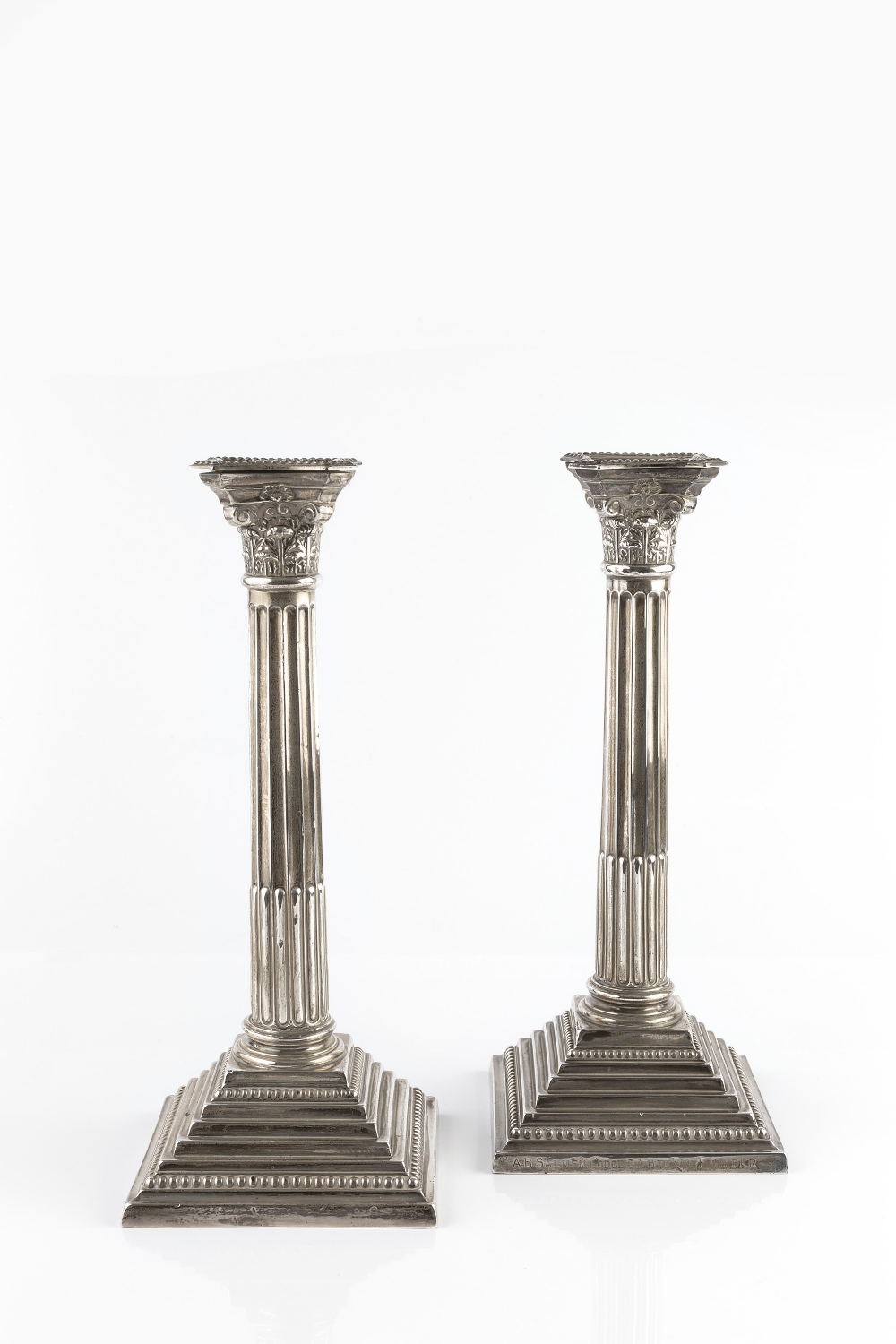 A PAIR OF SILVER CORINTHIAN CANDLESTICKS, with beaded drip pans, fluted columns, and beaded