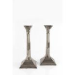 A PAIR OF SILVER CORINTHIAN CANDLESTICKS, with beaded drip pans, fluted columns, and beaded