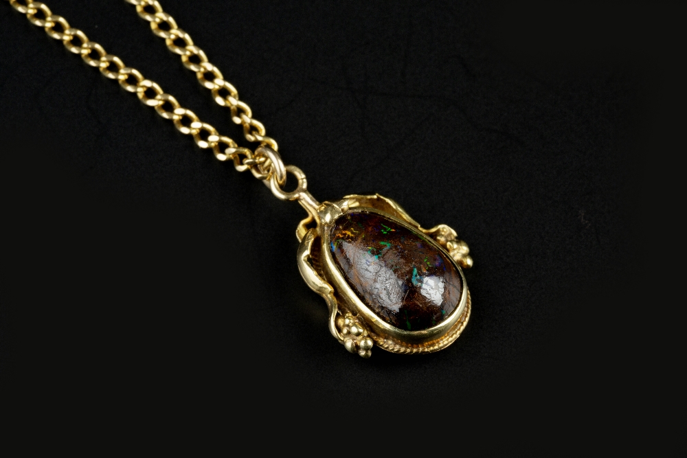 A BOULDER OPAL PENDANT ON CHAIN, the pear-shaped cabochon boulder opal collet set to an Arts and