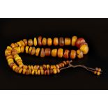 AN AMBER BEAD NECKLACE, comprising a single strand of graduated amber and amber coloured beads,