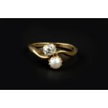 A DIAMOND AND HALF PEARL TWO STONE CROSSOVER RING, obliquely claw set with a cushion-shaped old-