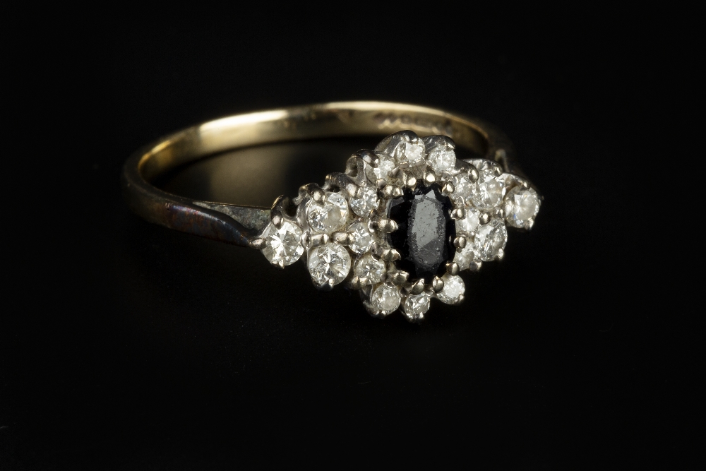 A SAPPHIRE AND DIAMOND CLUSTER RING, the oval mixed-cut sapphire claw set within a cluster of