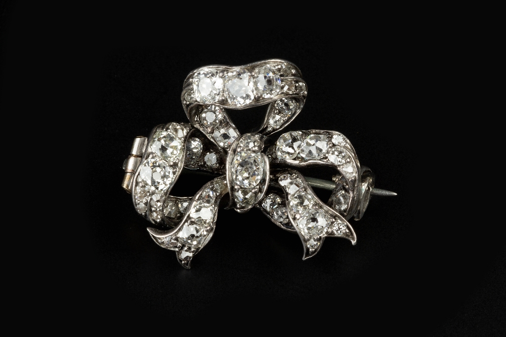 A DIAMOND SET BOW BROOCH, modelled as a loosely tied ribbon bow of graduated cushion-shaped old-