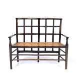 Attributed to Liberty & Co. Child's settee, circa 1900 stained wood, lattice back, over caned seat