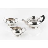 A SILVER THREE PIECE TEA SERVICE, of compressed circular form, the teapot with ebonised handle and