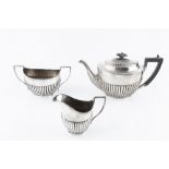 A SILVER THREE PIECE TEA SERVICE of half lobed form, the teapot with ebonised handle and knop, by