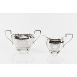 AN EDWARDIAN SILVER TWIN HANDLED SUGAR BASIN, and matching milk jug, of shaped outline, engraved