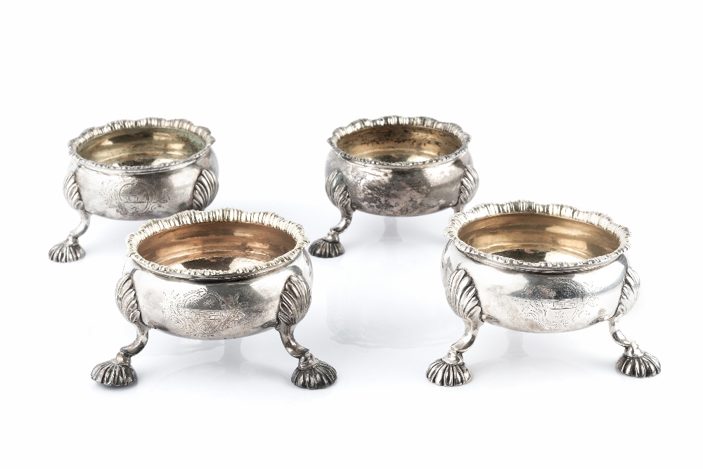 A SET OF FOUR GEORGE II SILVER CIRCULAR SALTS, with shaped borders, on shell capped scalloped