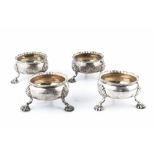 A SET OF FOUR GEORGE II SILVER CIRCULAR SALTS, with shaped borders, on shell capped scalloped