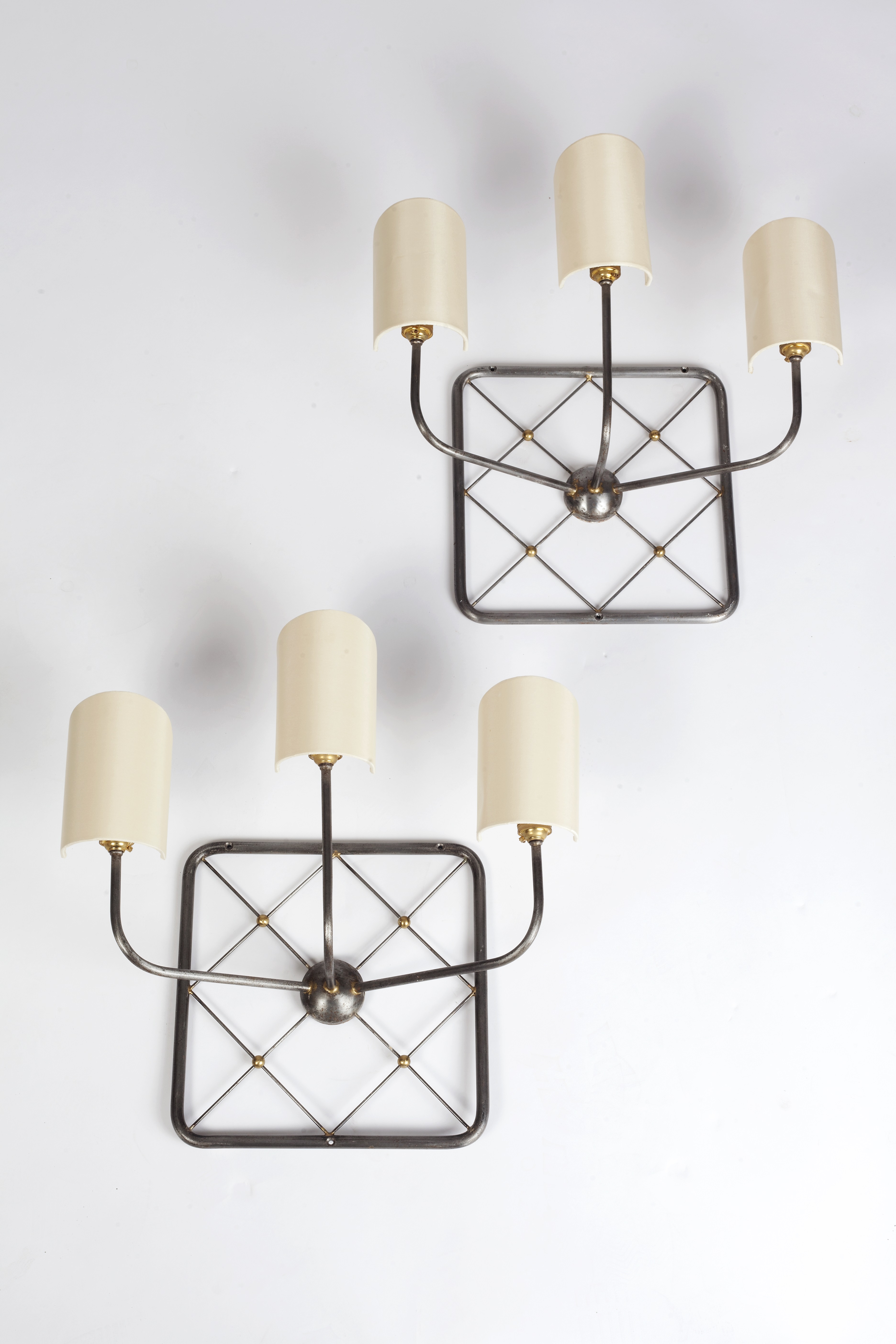 Manner of Jean Royere (1902-1981) Set of four 'Tour Eiffel' wall lights iron and brass, with cream