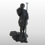 A Japanese patinated bronze figure of a boatman, standing with one arm raised,