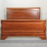 A modern cherrywood sleigh bed, with a slatted wooden base,